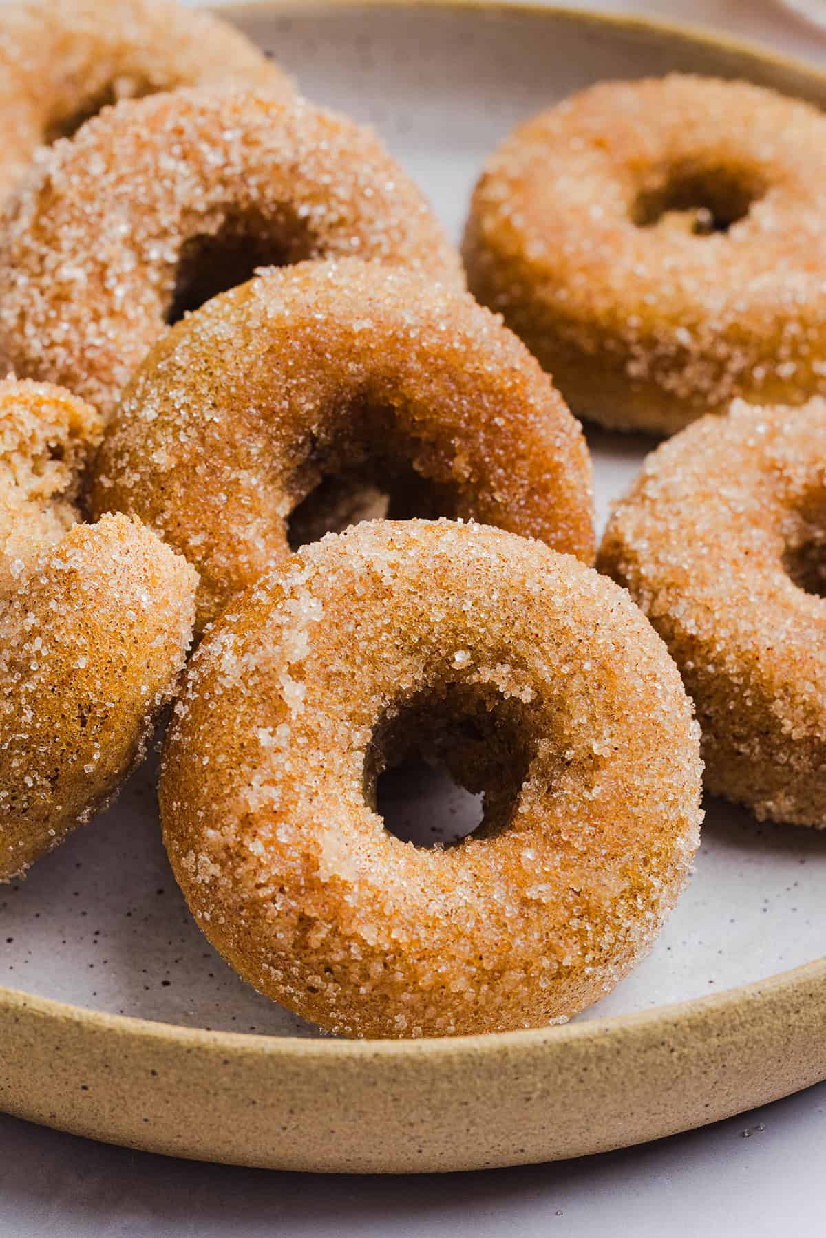 Soft Baked Apple Cider Donuts made healthier with whole wheat flour, applesauce and Greek yogurt for the perfect fall treat that comes together in just 20 minutes!  Loaded with warm spices and coated with cinnamon and sugar!